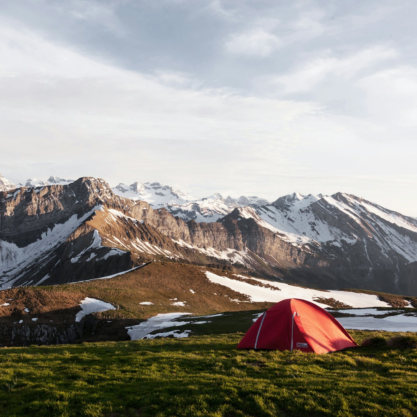 A tent pitched under mountains at dusk