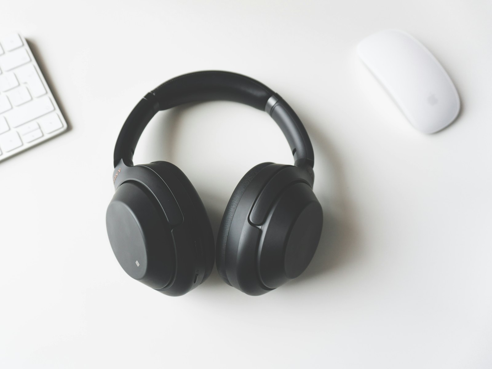 Over-ear noise cancelling headphones beside a keyboard and mouse