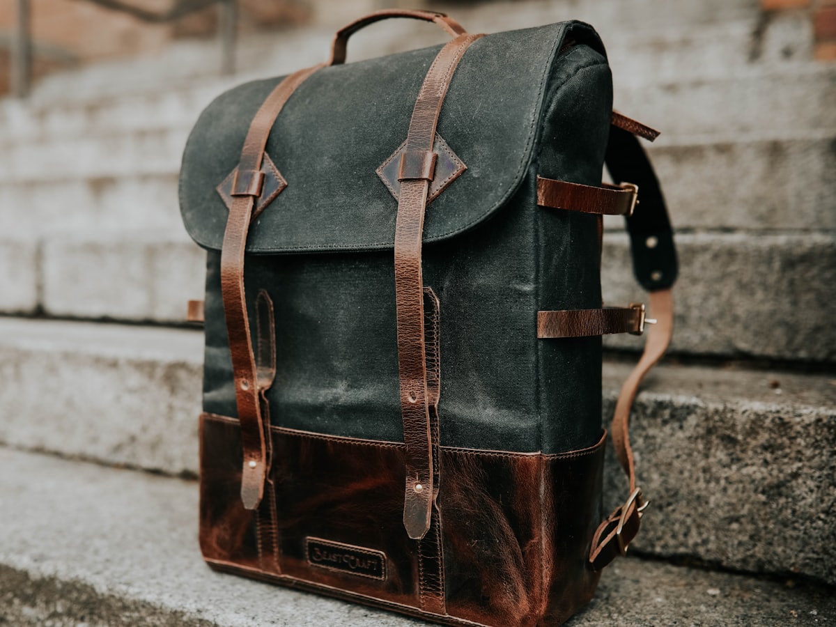 A waxed canvas and leather backpack resting on stone steps