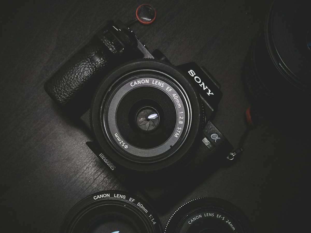 A mirrorless camera body and lenses on a dark surface